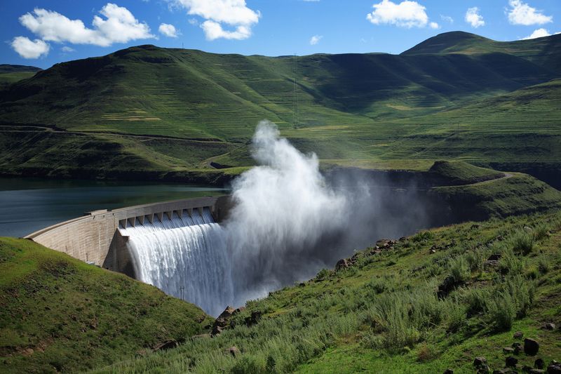 Water pouring from a dam spillway among green hills