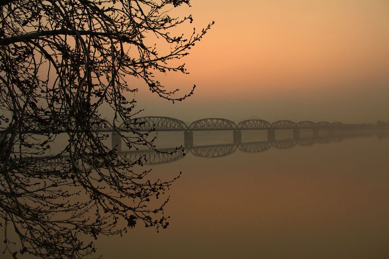 Steel bridge crossing a misty river at dawn